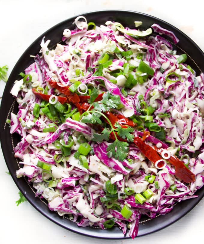 Creamy spicy chipotle coleslaw in a black bowl with red strips of chipotle peppers across the middle