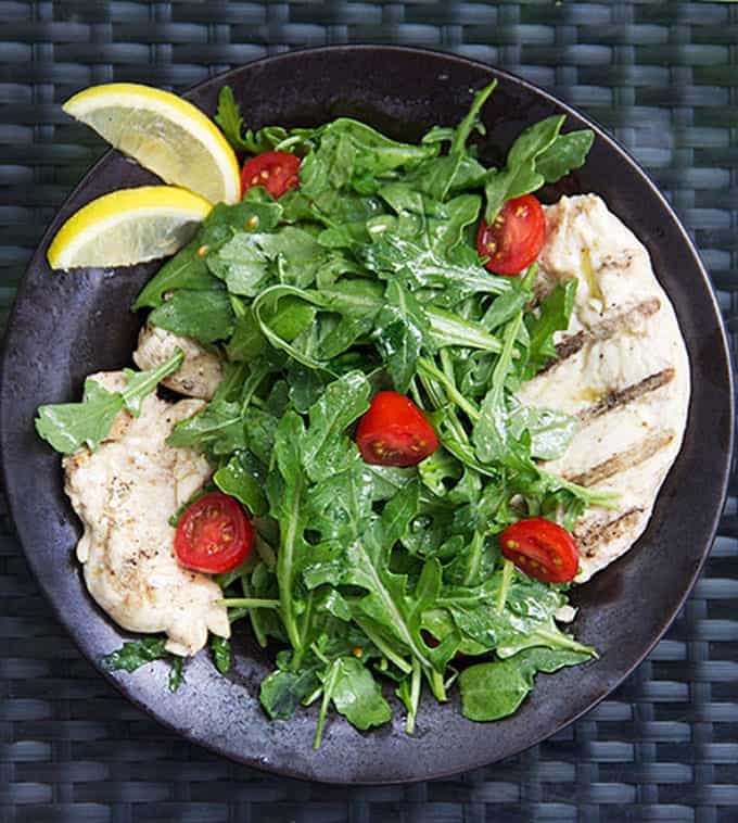 grilled chicken cutlet topped with arugula and cherry tomato salad.