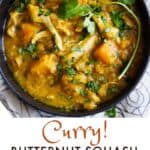 a black bowl filled with a stew of curry butternut squash, chicken and lentils