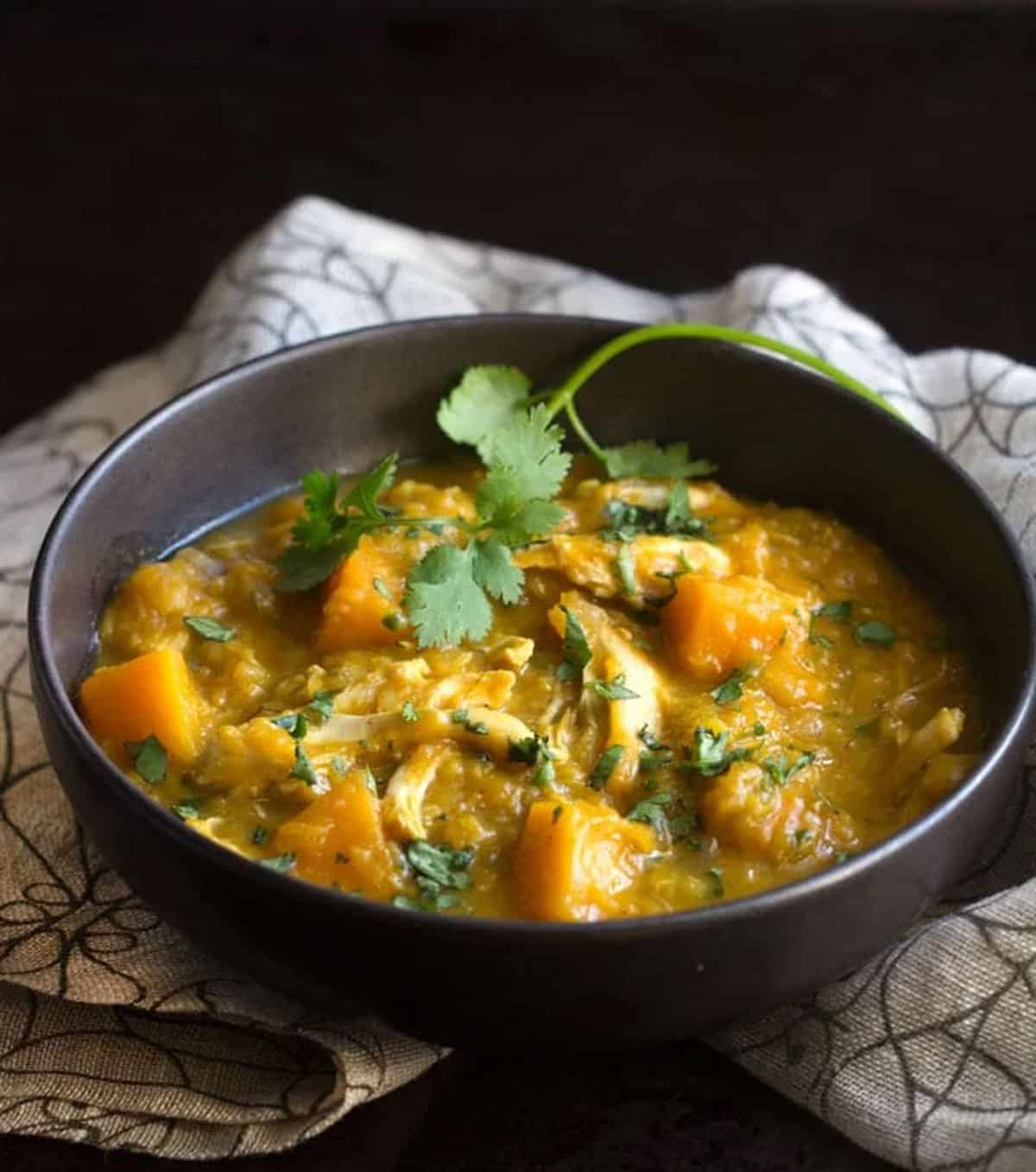 bowl of butternut squash and lentil stew with chicken, topped with chopped cilantro.