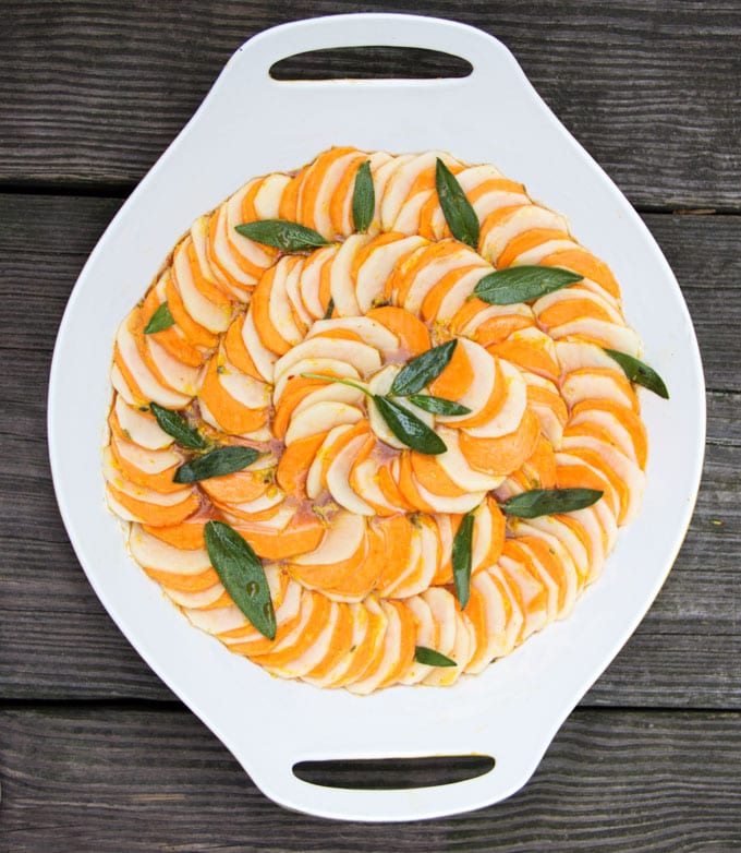 russet and sweet potato slices lined up in cocentric circles with sage leaves