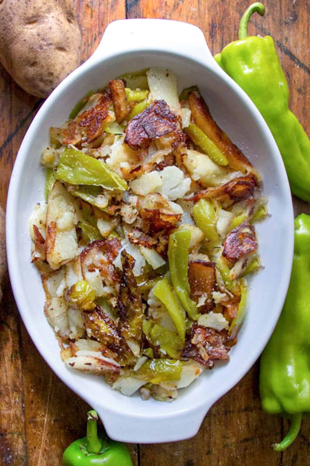 overhead shot of a white oval baking dish filled with fried potatoes and peppers