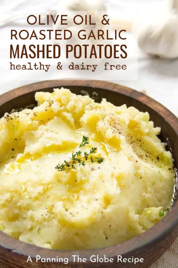 Pinterest Pin: olive oil and roasted garlic mashed potatoes in a brown wooden bowl with a sprig of thyme on top.