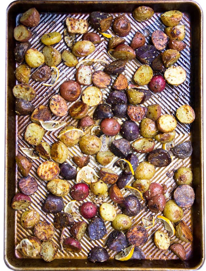 a rimmed baking sheet covered with halved roasted potatoes in different colors