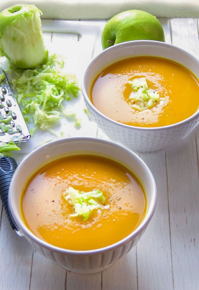 two bowls of curried butternut squash soup with shredded green apple garnhish