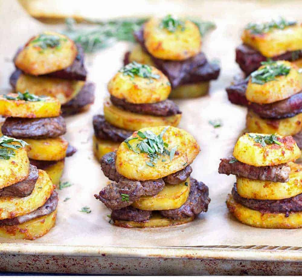 Baking sheet topped with rows of steak and potatoes stacks