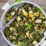 a white casserole filled with Indian Saag Aloo - spinach and potatoes