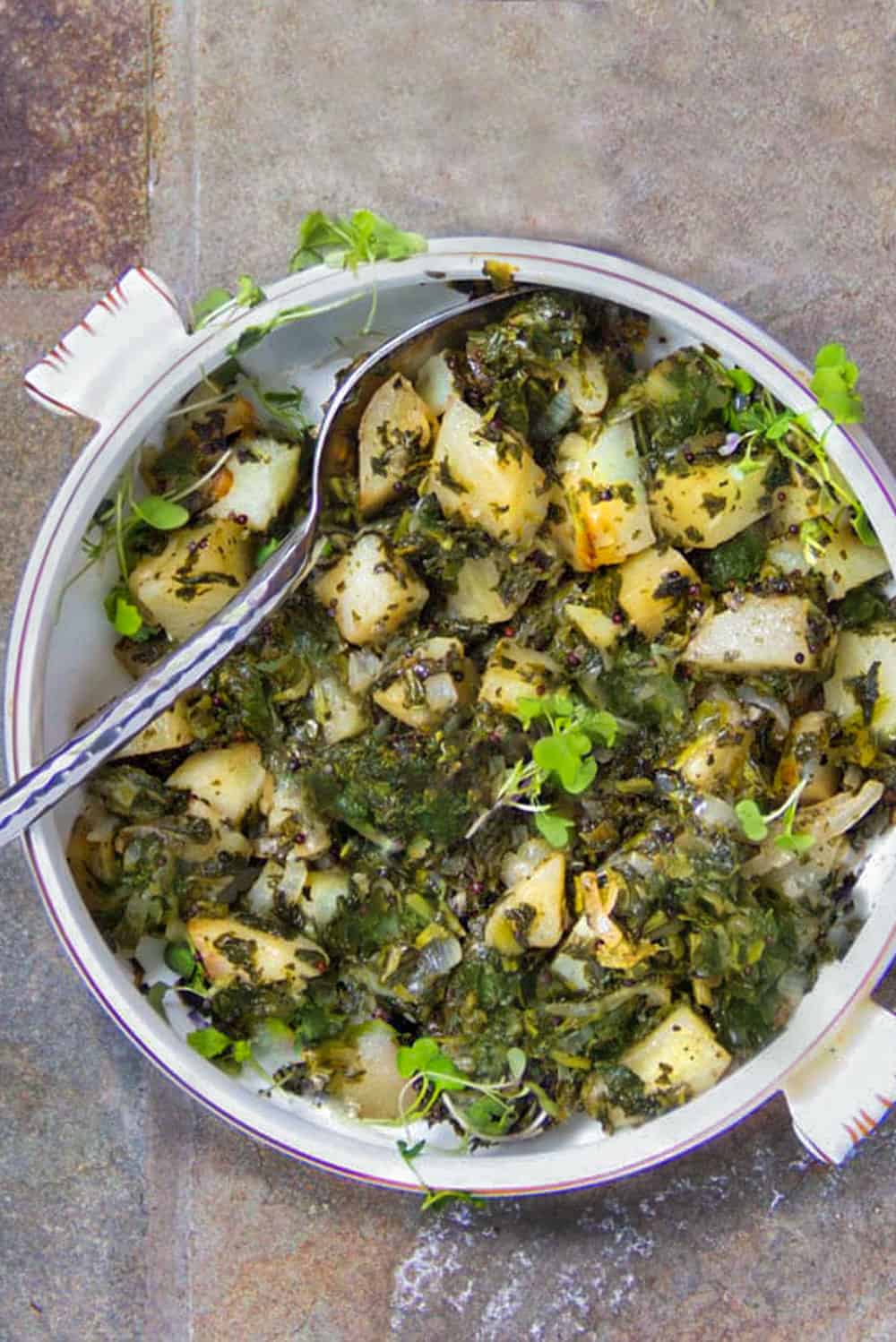 a white casserole filled with Indian Saag Aloo - spinach and potatoes