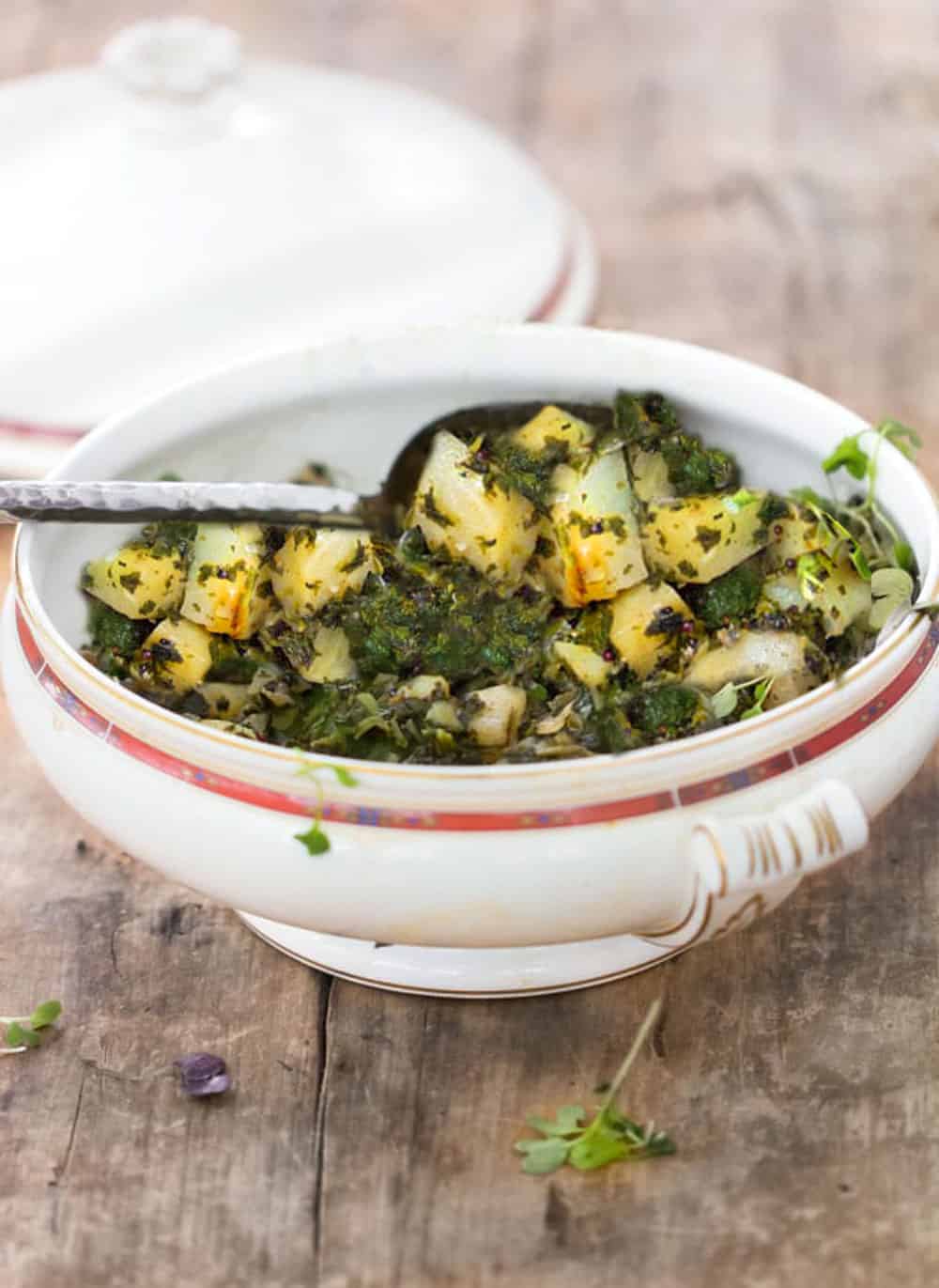 Indian spinach and potatoes, Saag Aloo, in a white serving bowl