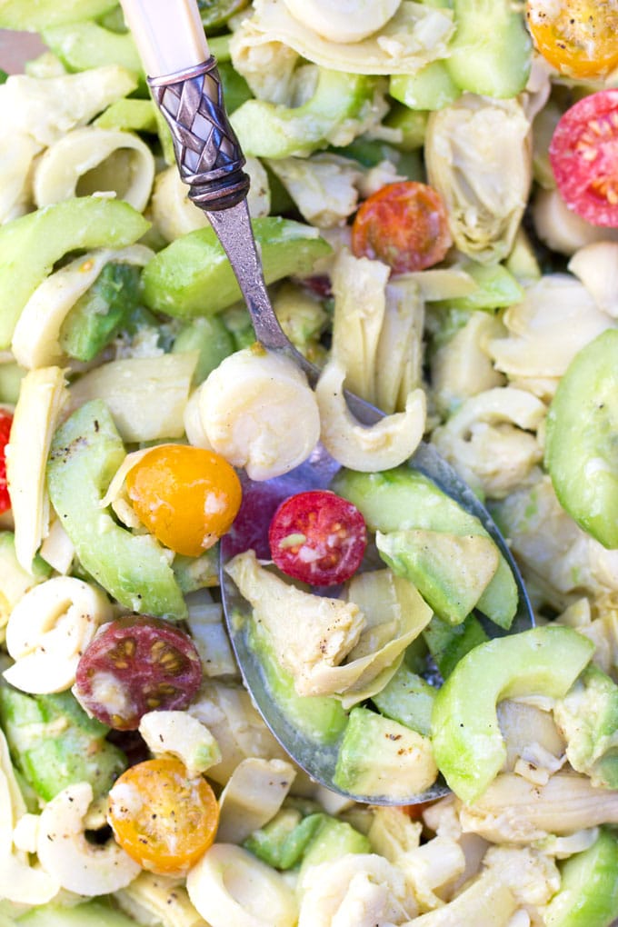 close up of a salad with artichokes, sliced cucumber, halved cherry tomatoes, sliced hearts of palm and artichoke hearts