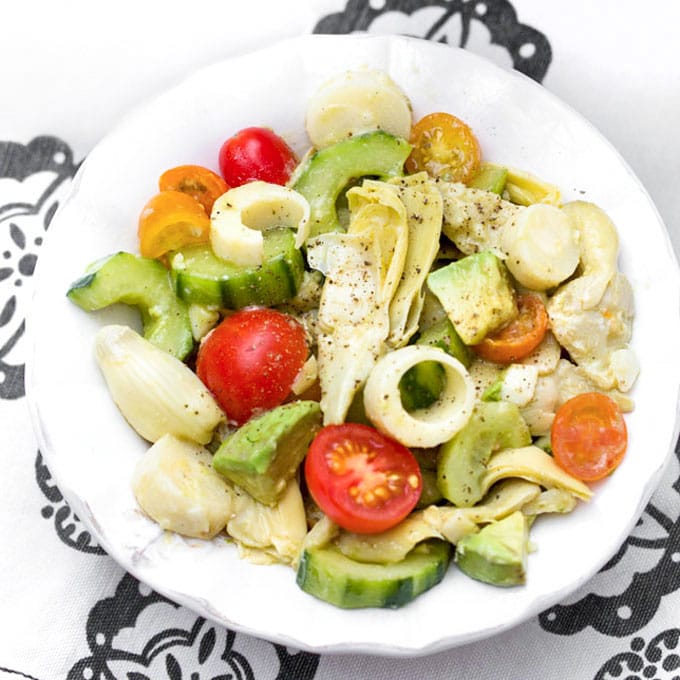 bowl with hearts of palm salad with cucumbers, artichoke hearts, avocados and cherry tomatoes