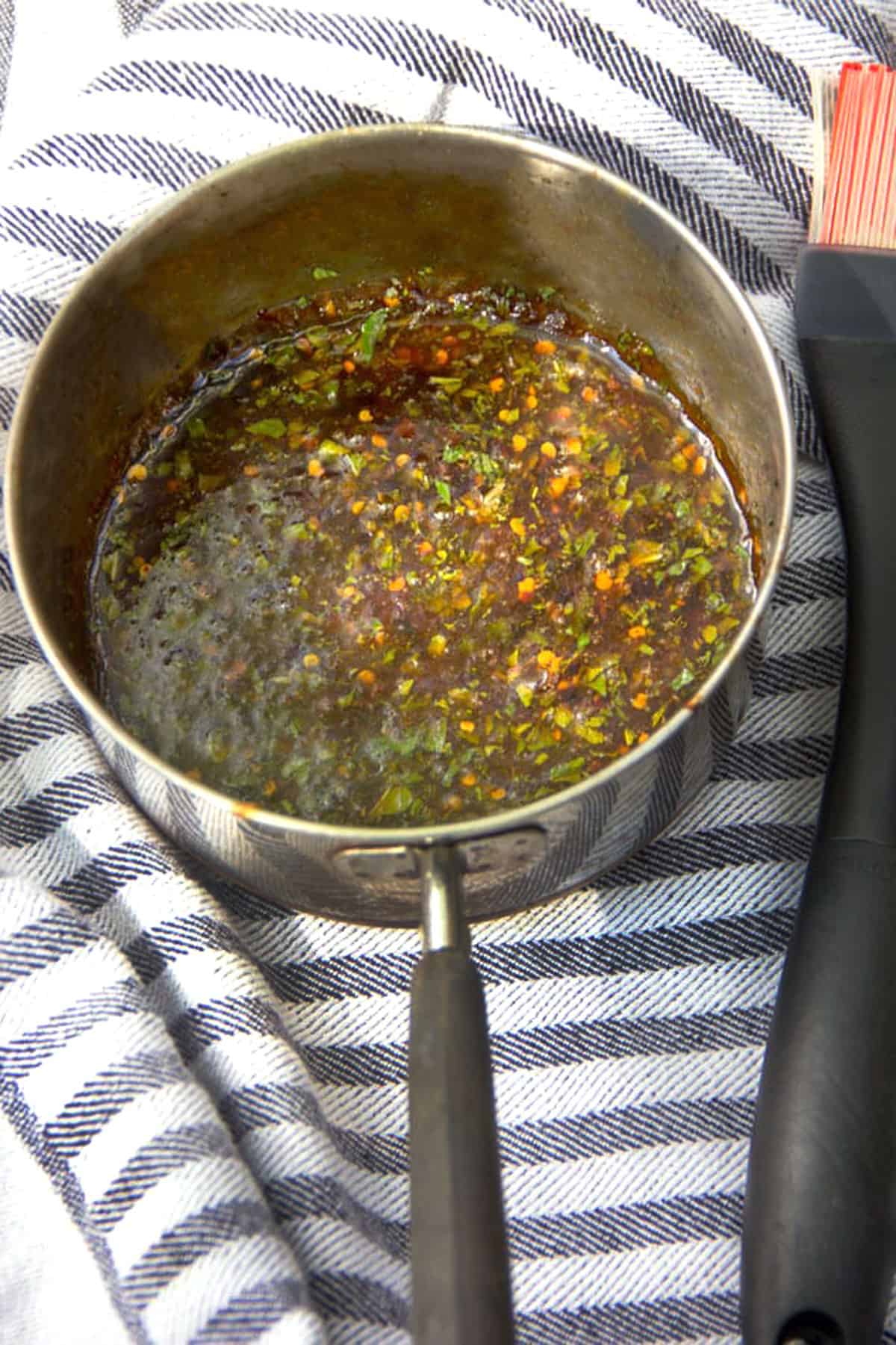 saucepan on a striped dish towel, filled with mint pepper glaze.