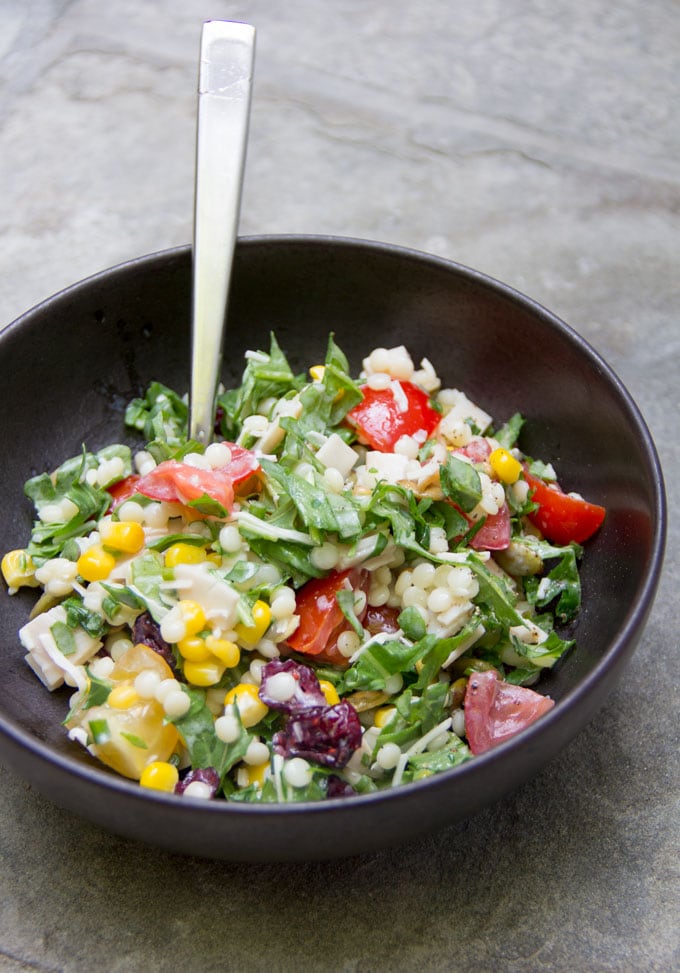 Chopped salad in a black bowl with a spook sticking up out of it