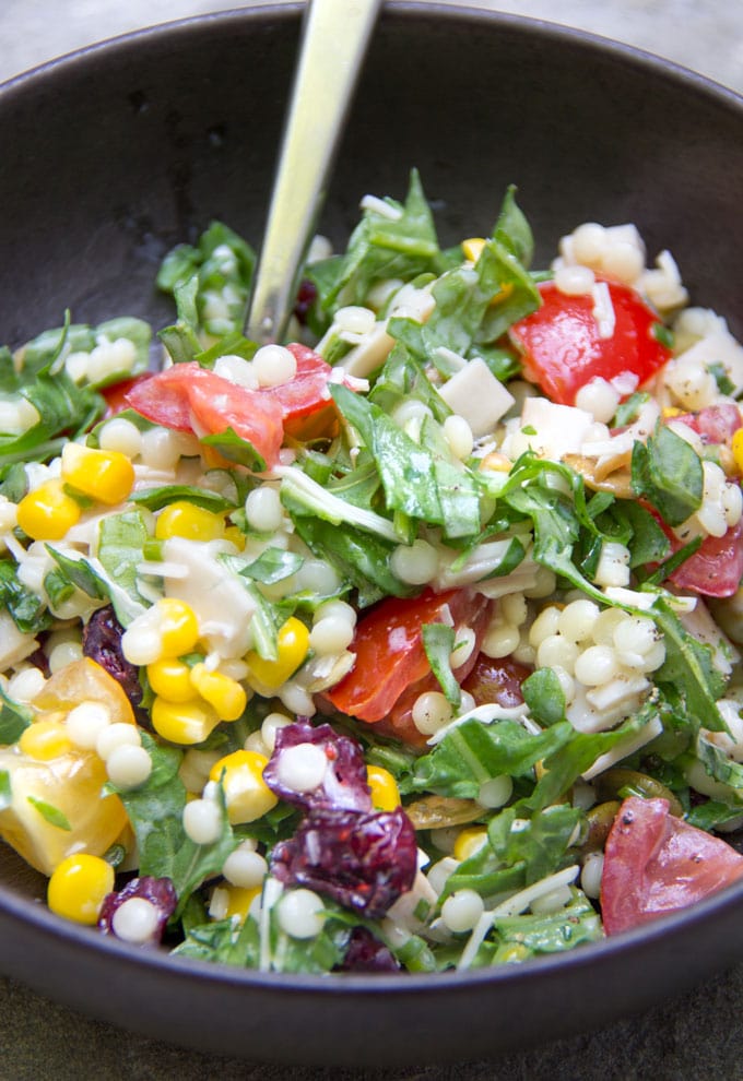 close-up of chopped salad with arugula, turkey, tomatoes, corn, couscous and cheese