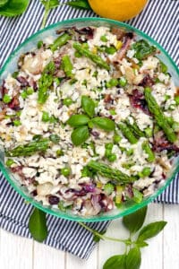 Mediterranean Rice Salad in a round green glass bowl with a sprig of basil in the middle