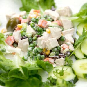 Close up of colorful Brazilian chicken salad with carrots, pease and olives, on a bed of lettuce.