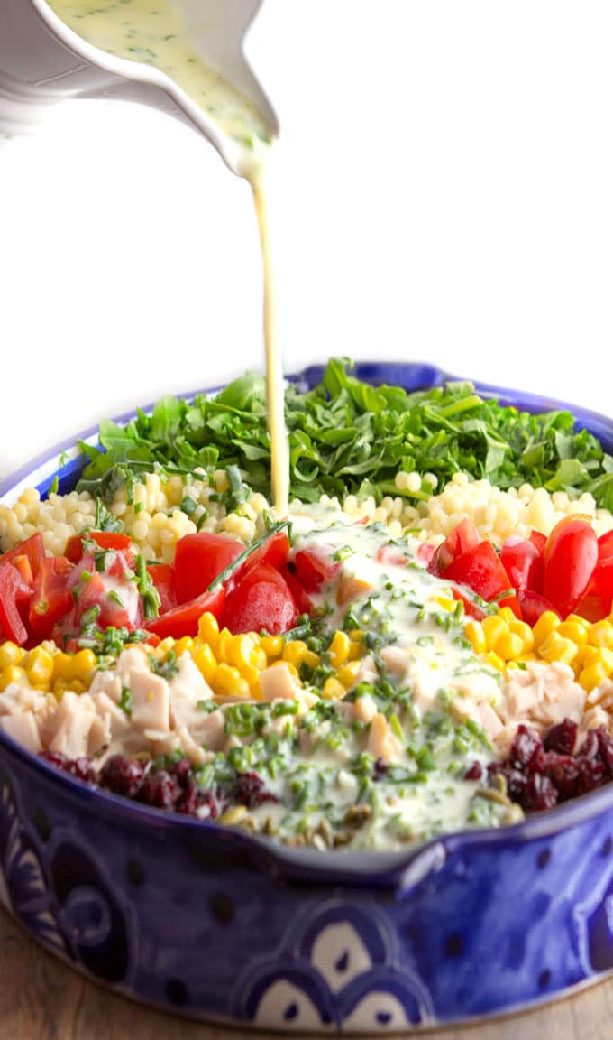 Herbed buttermilk dressing pouring out over a chopped salad 