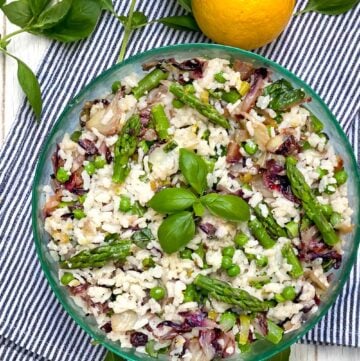 Mediterranean Rice Salad in a round green glass bowl with a sprig of basil in the middle