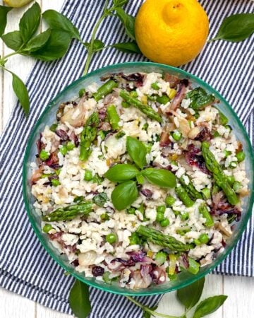 Mediterranean Rice Salad in a round green glass bowl with a sprig of basil in the middle