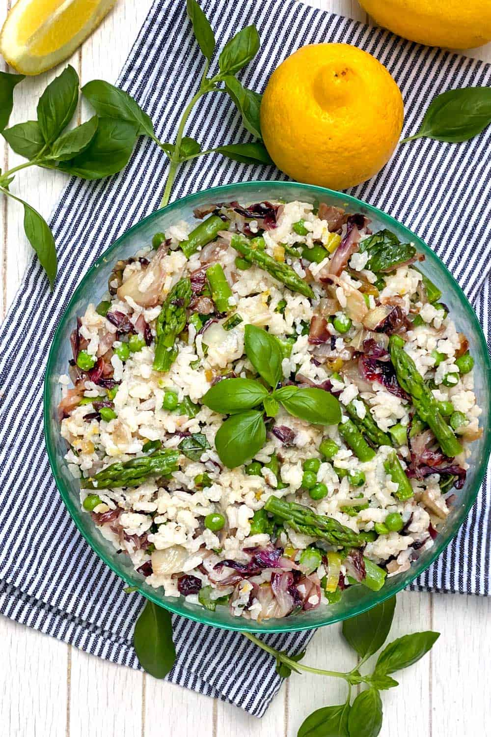 Mediterranean Rice Salad in a round green glass bowl with a sprig of basil in the middle
