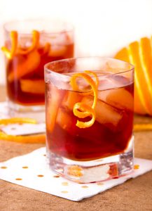 two deep red boulevardier cocktails with garnishes of swirly orange peel dangling from the glassThe Boulevardier is complex, refreshing and totally delicious - a fantastic drink recipe to add to your cocktail repertoire. With or without the smoke, these will be loved by all!