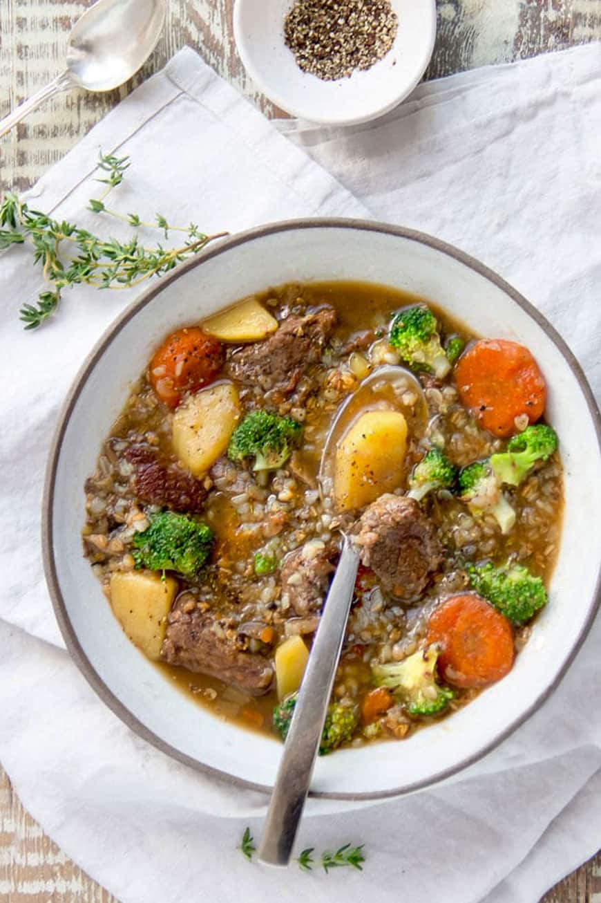 overhead shot of a white bowl filled with beef buckwheat soup with chunks of beef, potatoes and carrots