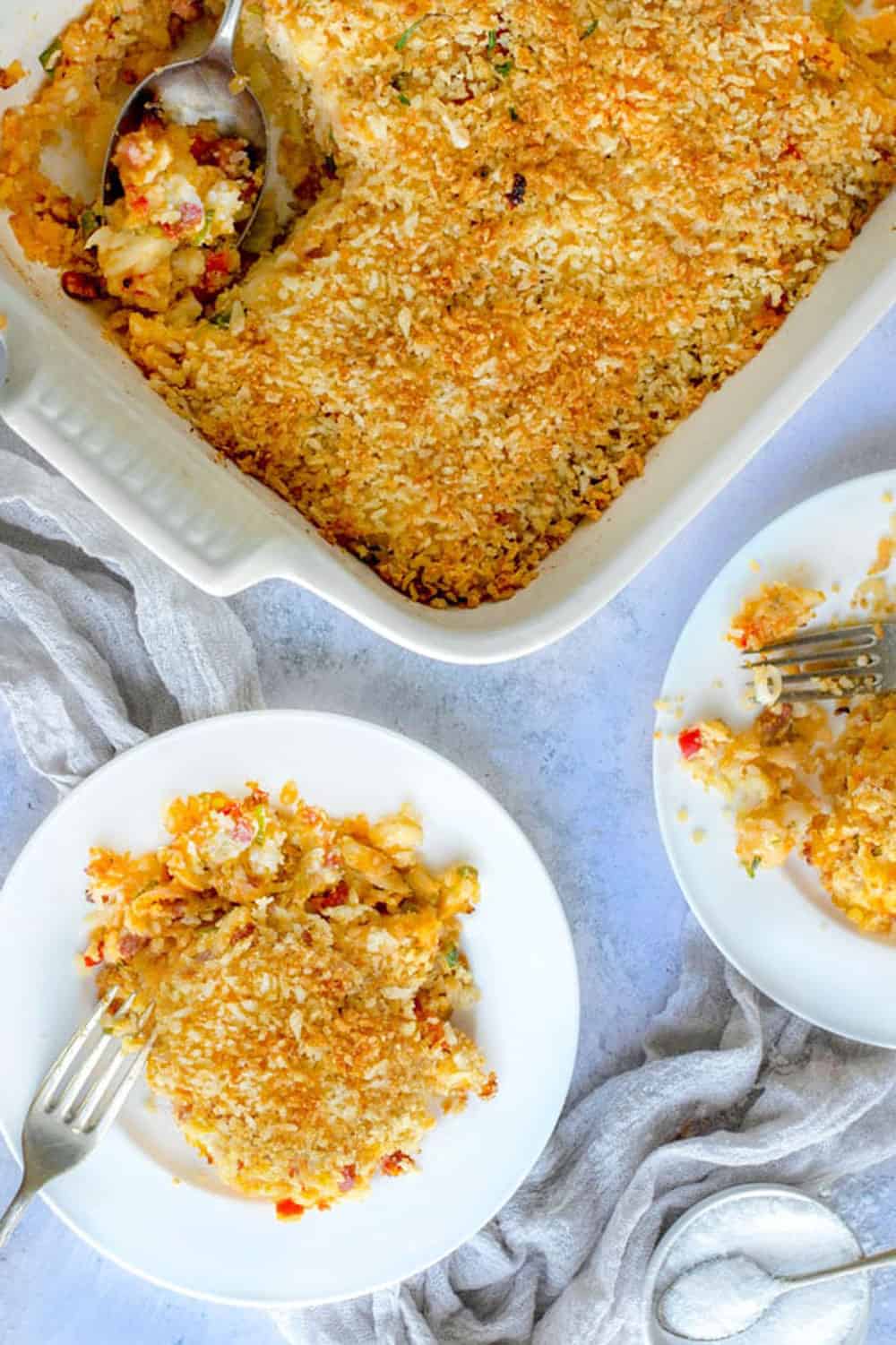 funeral potatoes in a rectangular casserole dish from above, with a plate that has a portion.