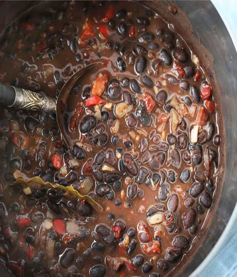 A pot of Cuban black beans with a decorative spoon in the beans.