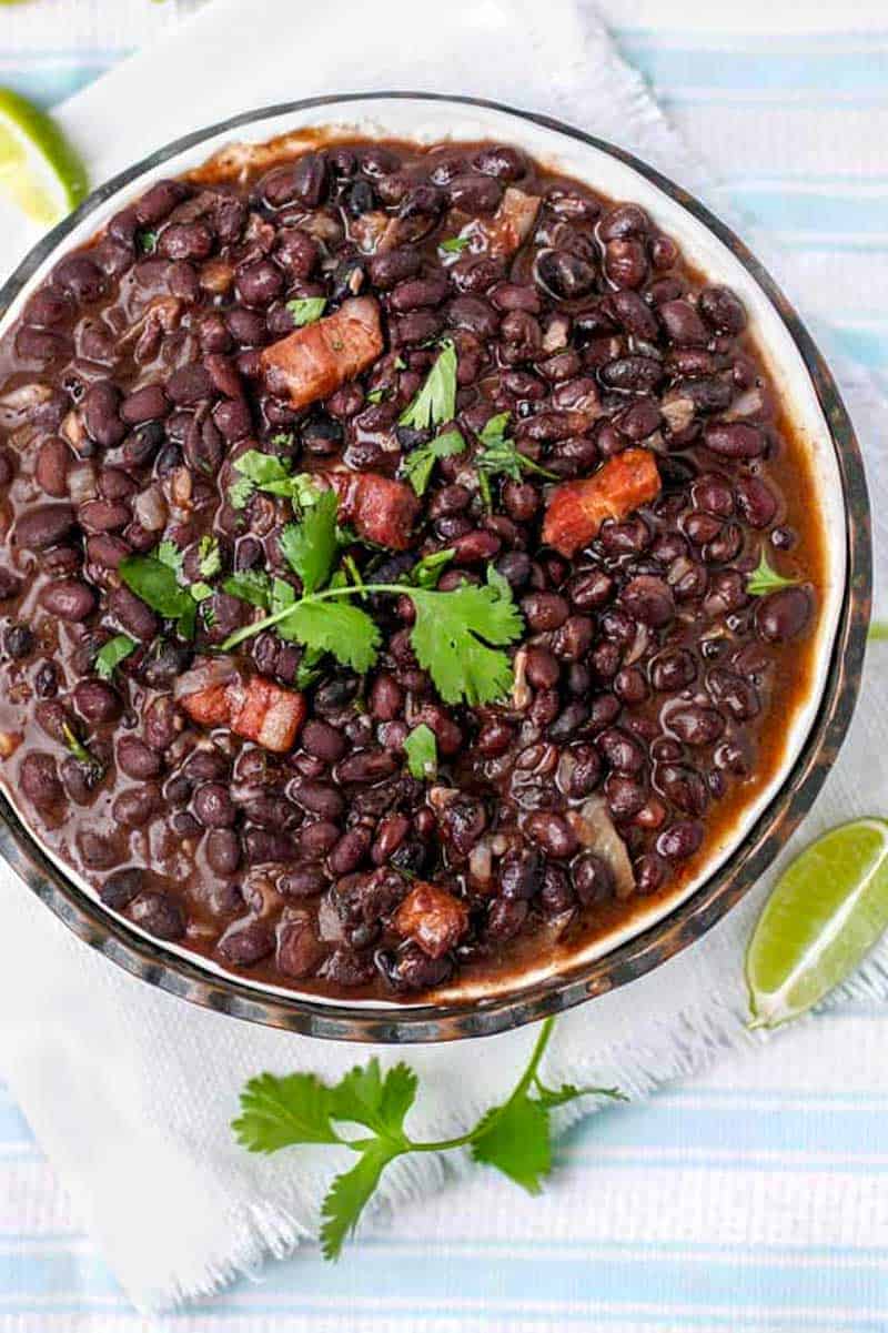 a bowl of cuban black beans garnished with a cilantro sprig