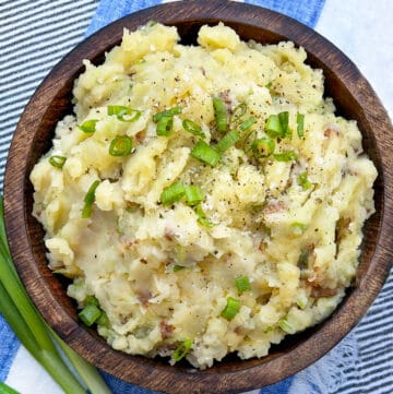 wooden bowl filled with red skin mashed potatoes flecked with chopped scallions