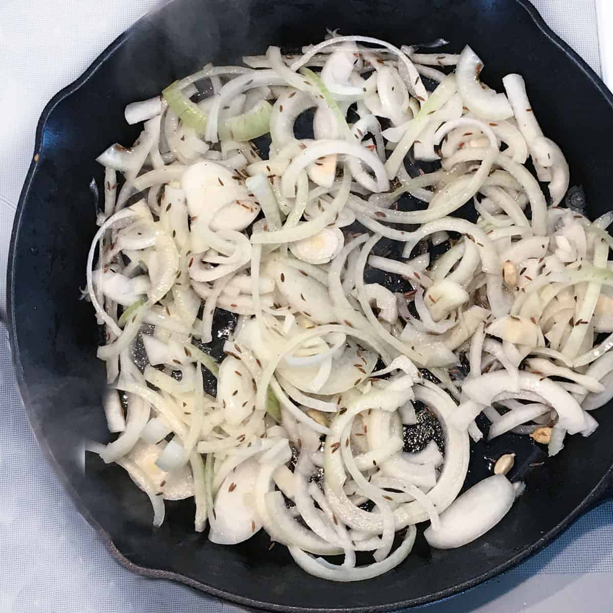 Sliced onions cooking in a cast iron skillet