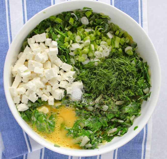 a bowl with the filling ingredients for Greek spinach pie with potato crust