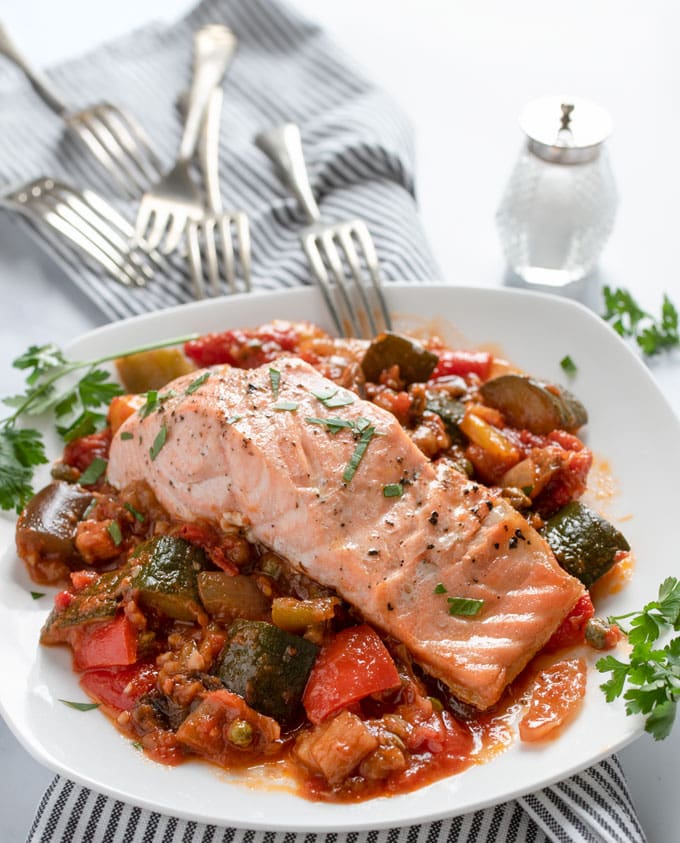 simple broiled salmon on a bed of ratatouille with a bunch of forks in the background