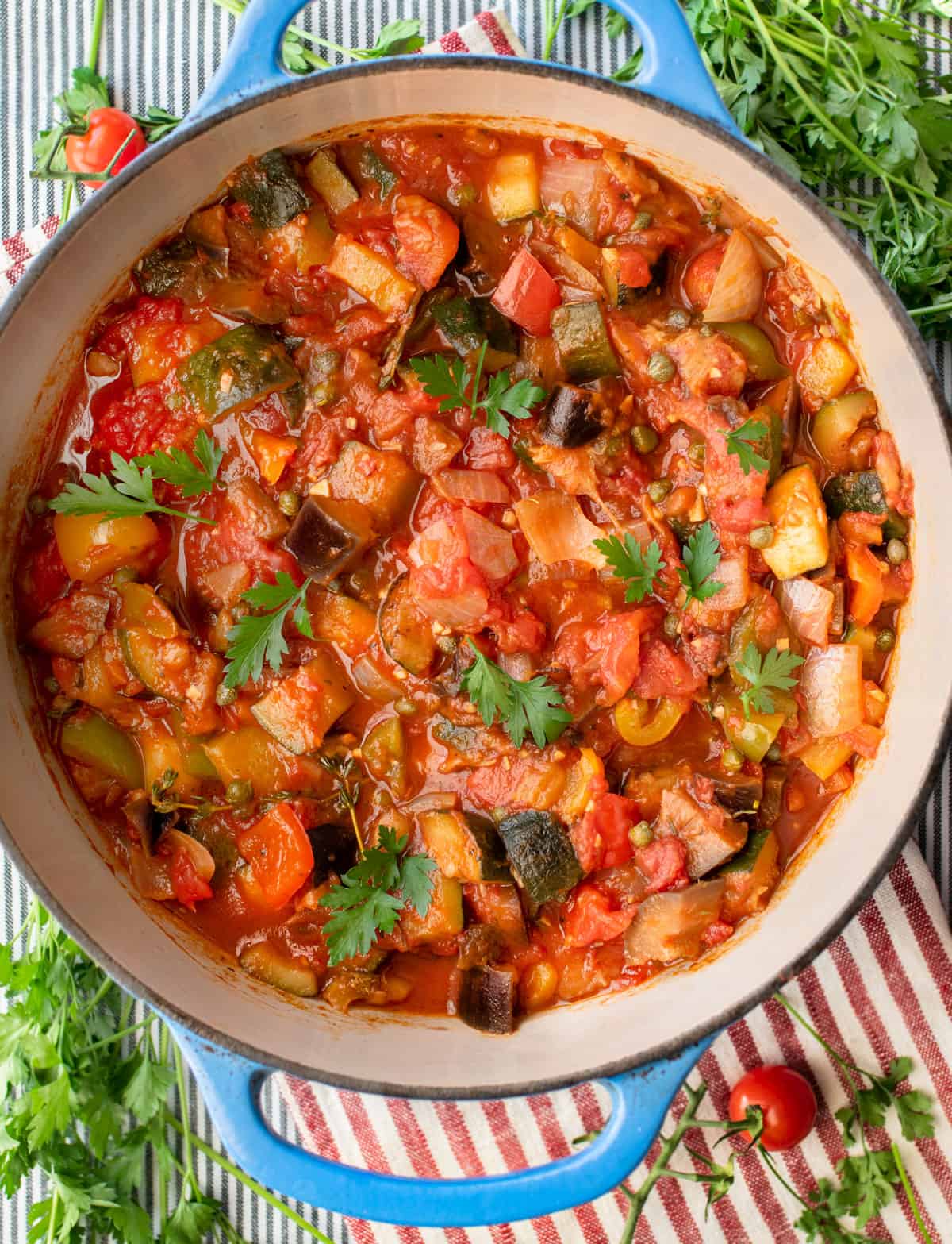 colorful ratatouille in a round Dutch oven topped with delicate parsley leaves