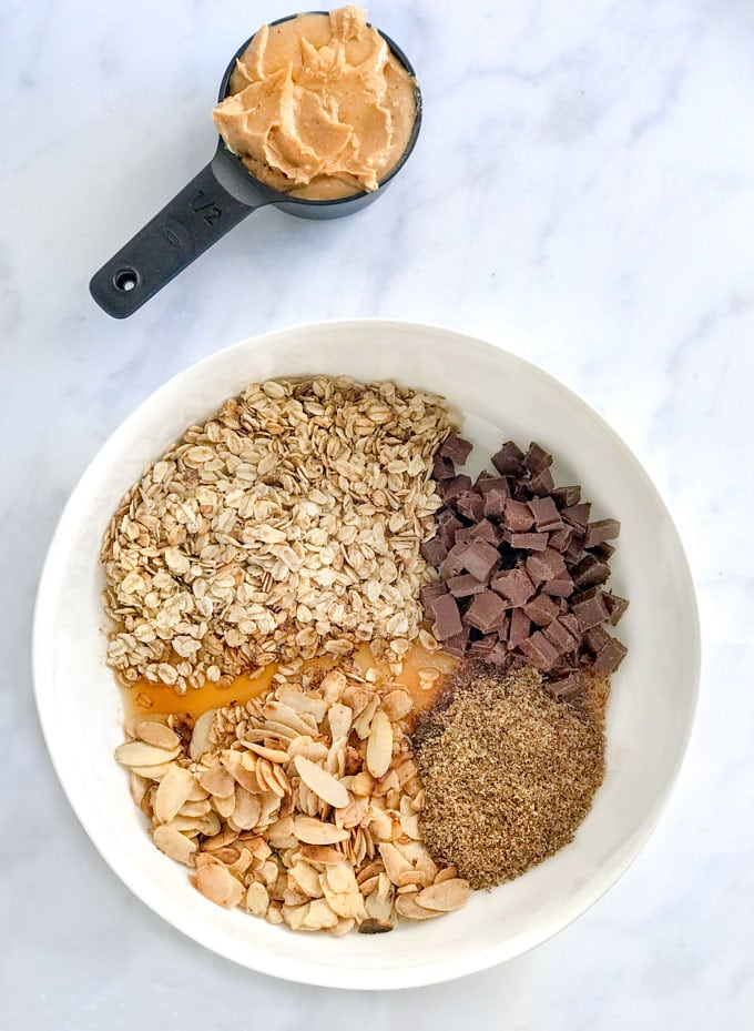 Peanut butter and a bowl with oats, almonds, flax, chocolate chips and maple syrup. No bake oatmeal peanut butter energy bites
