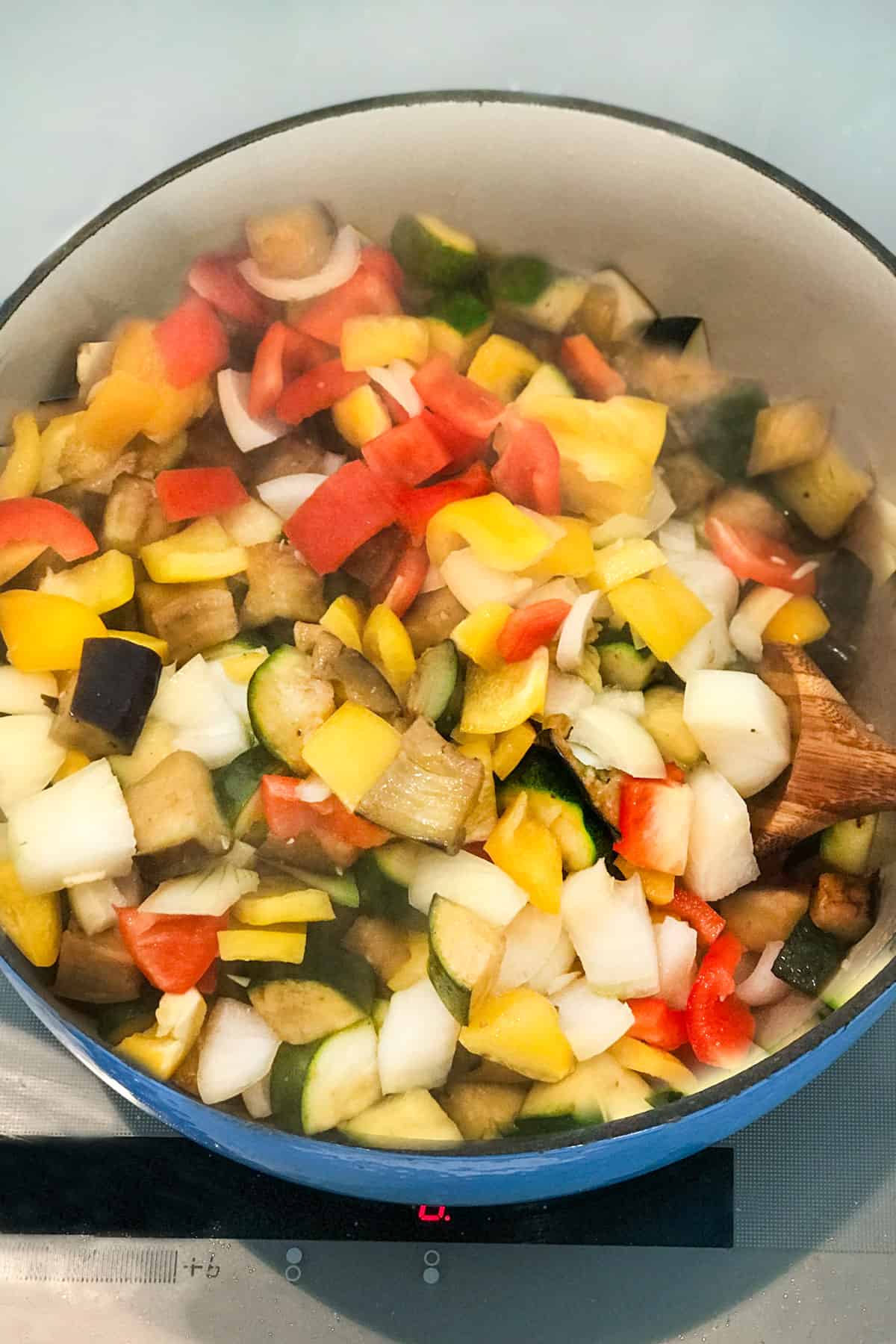 cubes of zucchini and eggplant with chopped onions and bell peppers in a dutch oven
