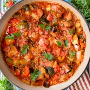 Dutch oven on a striped cloth, filled with ratatouille