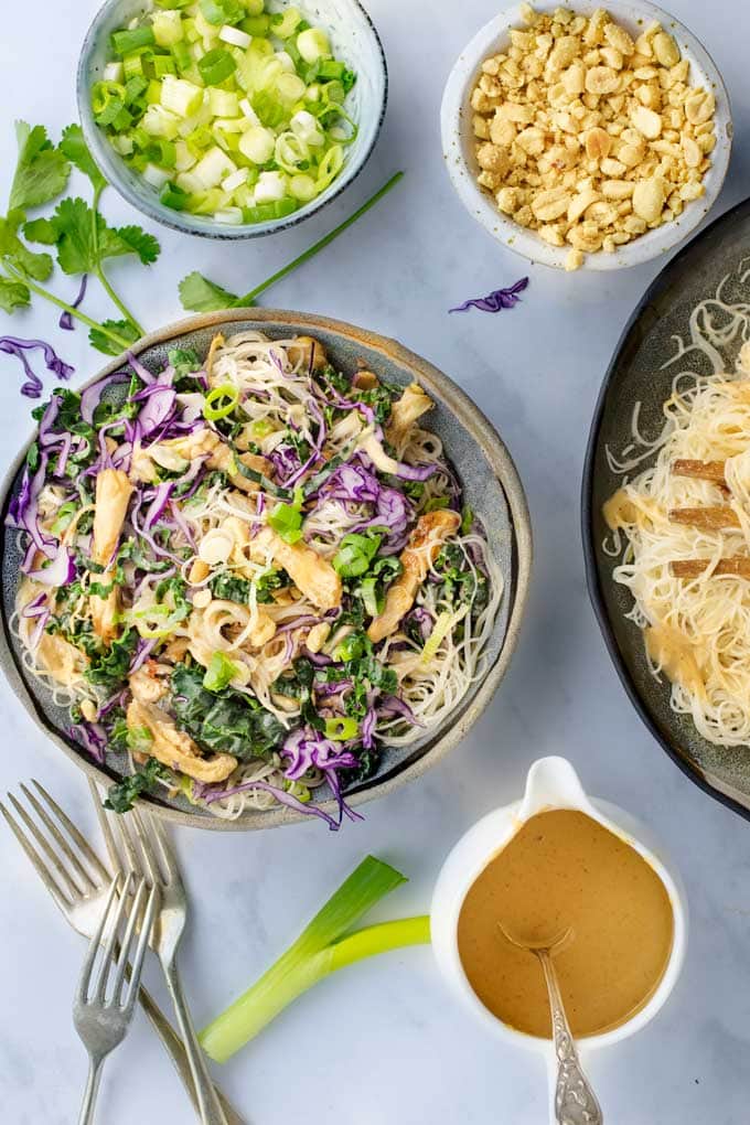 Thai Noodle salad bowl with peanut sauce and little bowls of peanuts and scallions