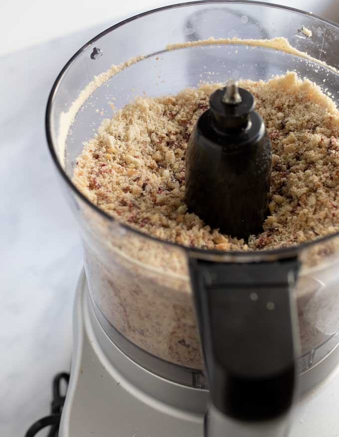 Close up of the bowl of a food processor filed with ground dried fruits and nuts