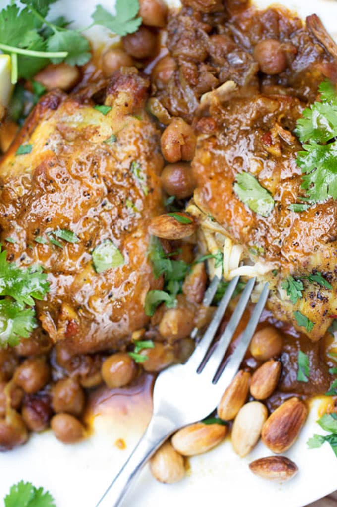 two piece of chicken tagine with chickpeas and a fork and a sprinkling of cilantro