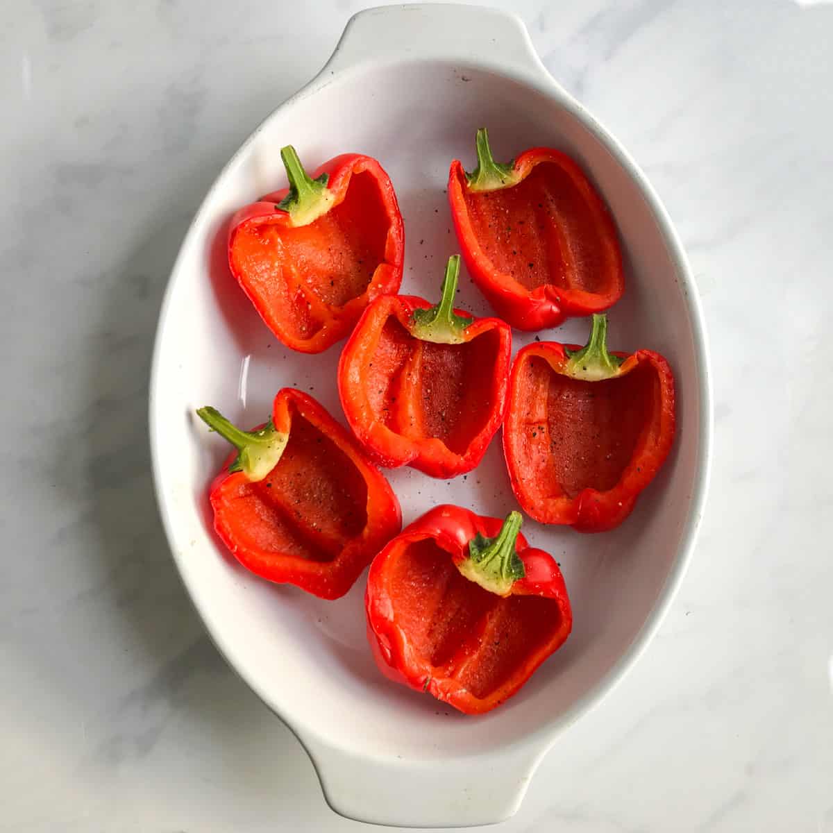 6 hollowed out red bell pepper halves, skin-side-down in an oval porcelain baking pan
