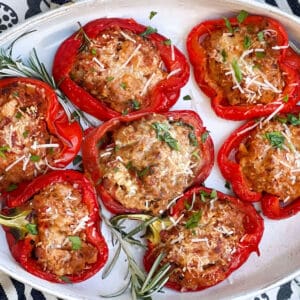 7 stuffed peppers topped with grated parmesan, in an oval casserole.