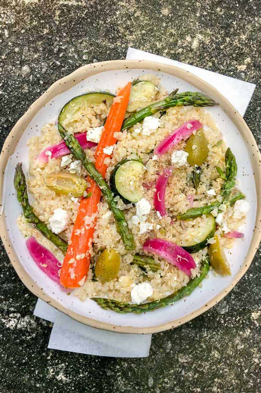 white bowl with quinoa and vegetables salad with feta
