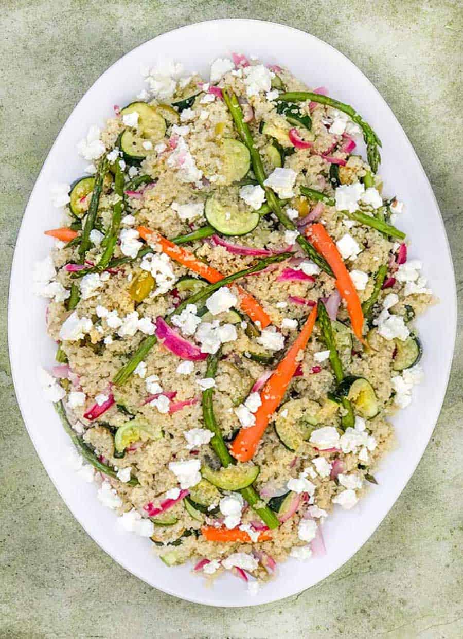 Oval white platter filled with quinoa and vegetables salad with feta