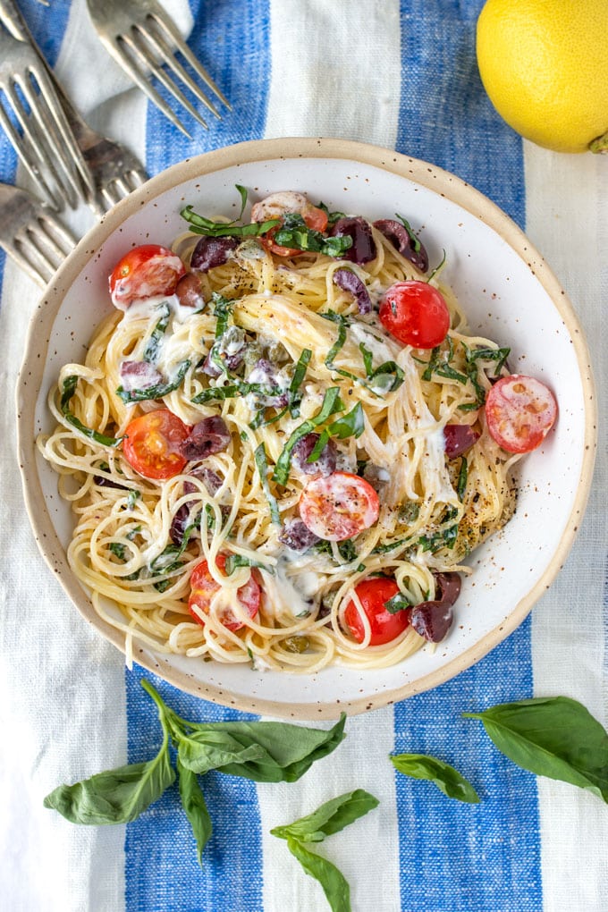 Bowl of summer pasta with goat cheese and cherry tomatoes and slivered fresh basil.