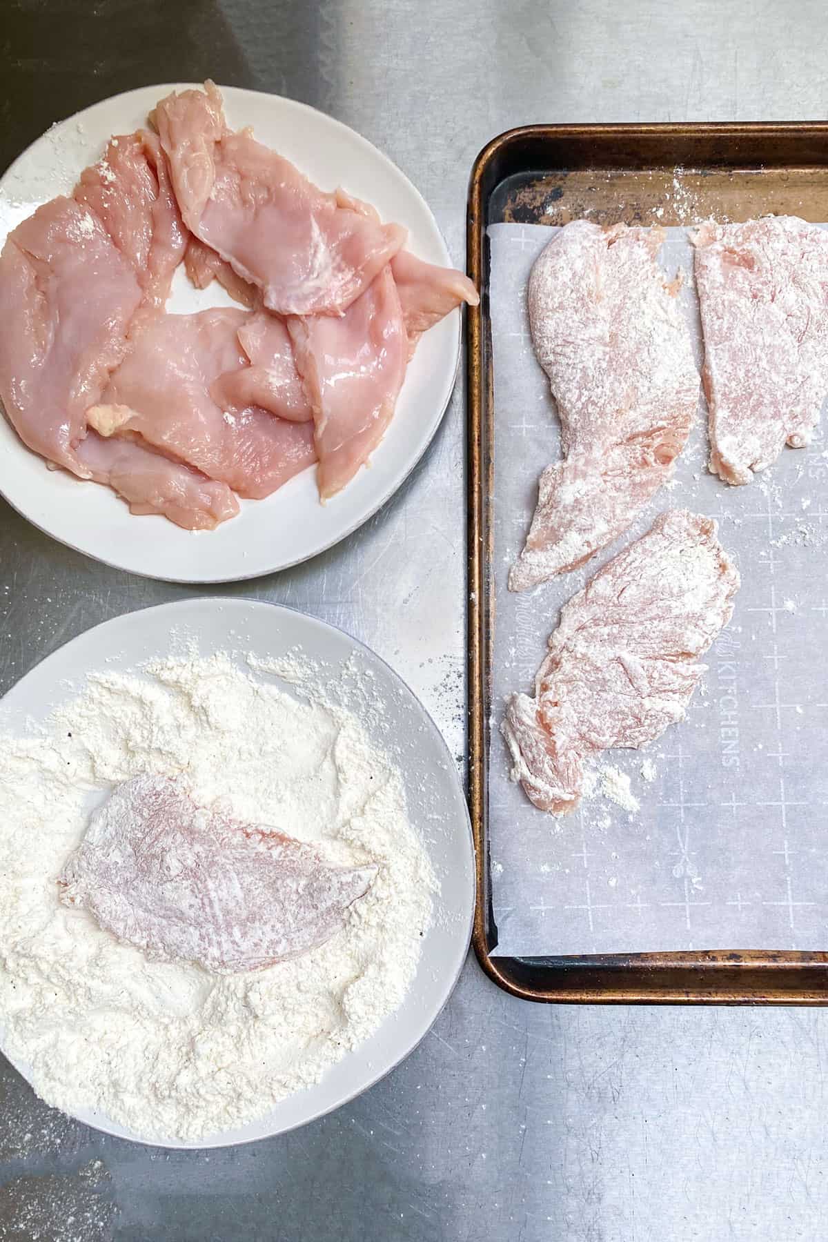 overhead shot showing the process of dredging chicken cutlets in flour and placing them on a parchment lined tray