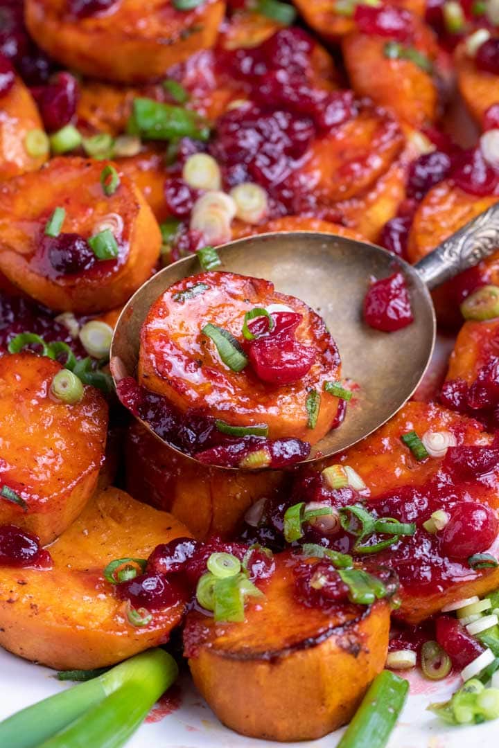 close up of roasted sweet potatoes with ruby red cranberry glaze and cranberries