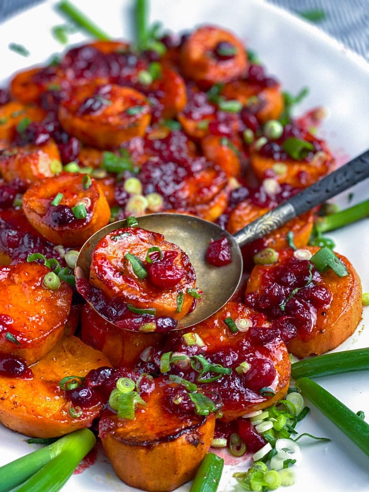 Platter of chili and brown sugar roasted sweet potatoes topped with cranberry citrus glaze