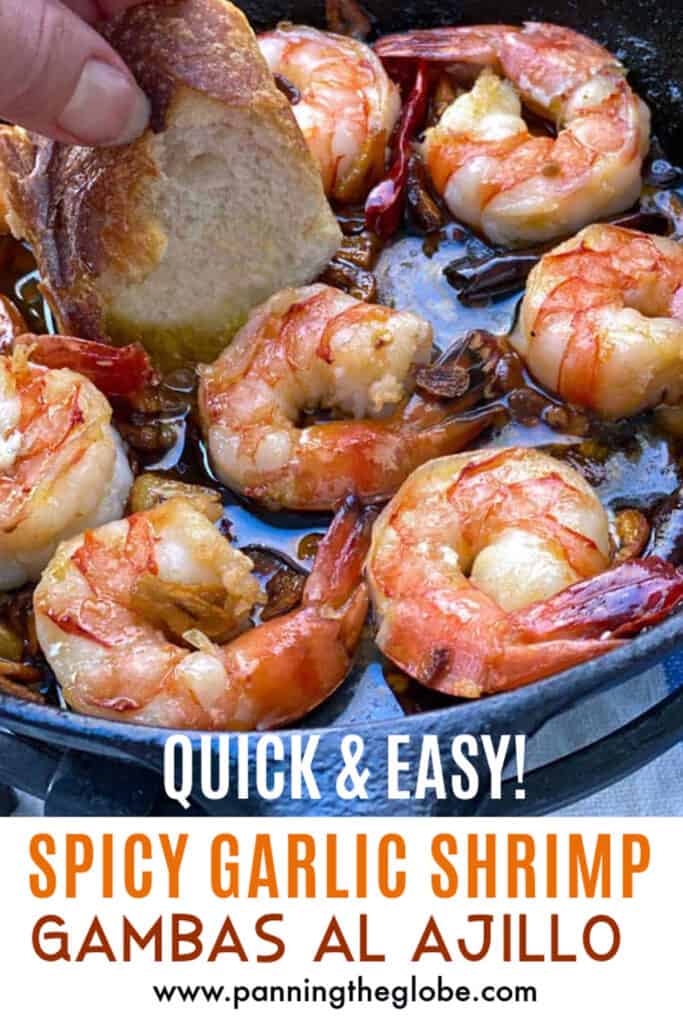 6 Spicy garlic shrimp in a cast iron skillet - a piece of bread being dunked in