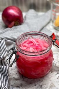 glass jar filled with pink pickled red onions.